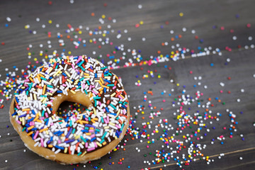 donuts with chocolate frosting, topping sprinkles donut Colorful variety and Variety of flavors mix of multi colored sweet donuts with frosted sprinkled on a wooden background. top view