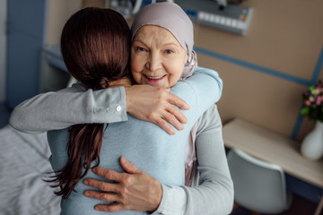 happy senior woman in kerchief embracing daughter in hospital