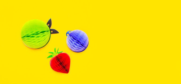 Flat lay bright tropical fruits of paper, strawberry, pineapple, apple, plum on yellow background top view copy space. Minimalistic creative summer food concept, origami paper fruit