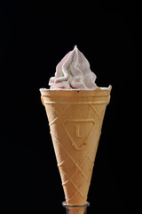 Beautiful and appetizing meringue ice-cream cake. On a black background with side light. Sugar powder in flight.