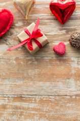 christmas, valentines day and holidays concept - gift box and heart shaped decorations on wooden background