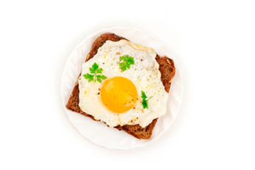 An egg cooked sunny side up on a toast, shot from the top on a white background with copy space