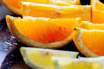 Slices of orange and lemon on black background