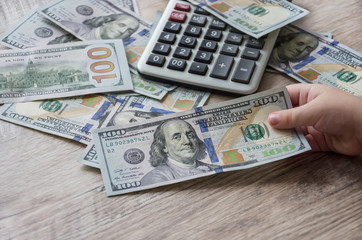 Fototapeta premium dollars, calculator and hand on a wooden table