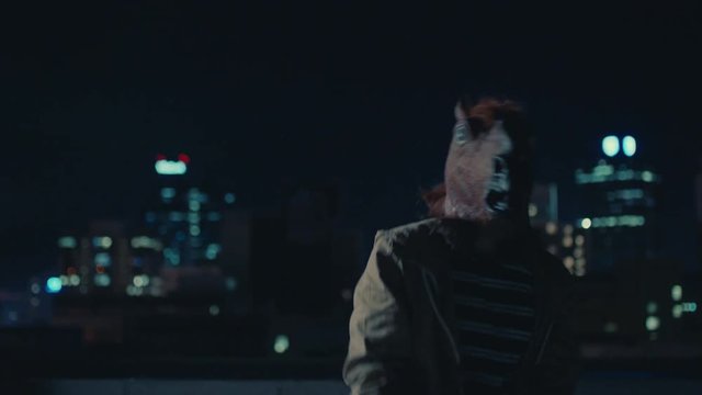 funny man wearing horse mask dancing on rooftop having fun performing silly dance moves celebrating weekend in urban city skyline