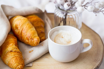 Coffee cup cappuccino with cream and tasty baked croissants. Morning breafast with croissants buns and fresh coffee