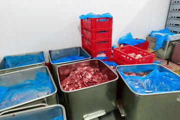 Steel containers with the large pieces of raw meat at the meat factory.