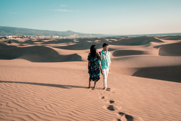 couple walking during sunset in the desert sand dunes of Maspalomas Gran Canaria, Maspalomas desert beach Gran Canary