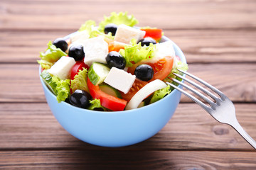 Fresh vegetable salad with fork on brown wooden background