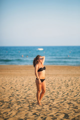 Fototapeta na wymiar Sexy lady in bikini sunbathing on a sandy beach. Fashion model