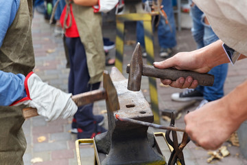Work with hammers on the anvil in the street forge workshop.