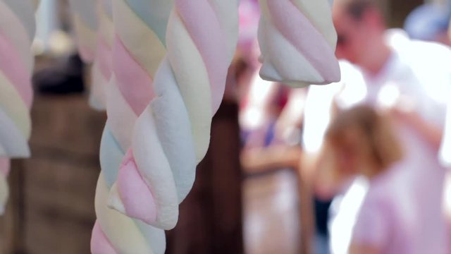Colourful flump marshmallows hanging from a street market stall.