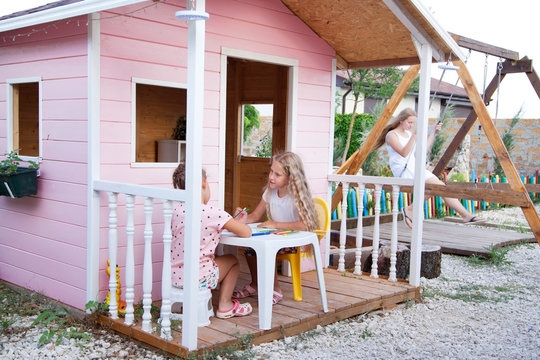 Little girls talking in the children's play house in a yard