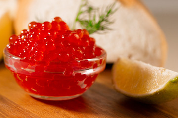 red caviar in glassware on wooden background with space for text