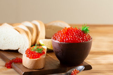 red caviar in a ceramic dish on a wooden background in a rustic style with space for text