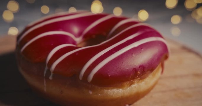 Close-up Dolly shot of a red donut on a bokeh background.