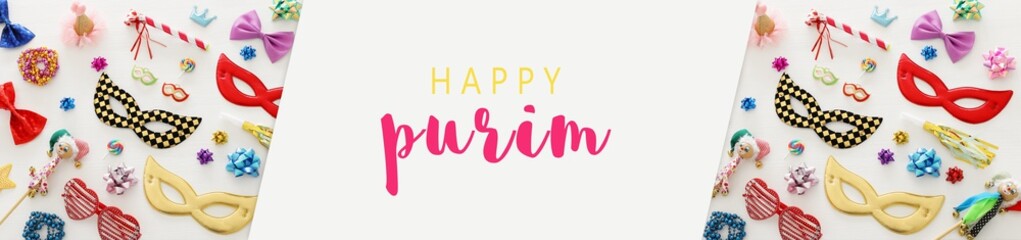 carnival party celebration concept with mask and colorful party accessories over white wooden background. Top view.