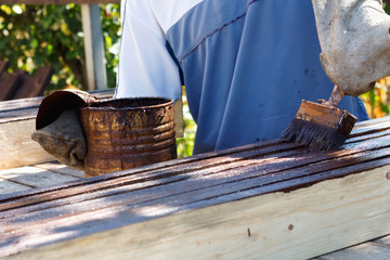 Male worker in old glove is painting boards for home decoration
