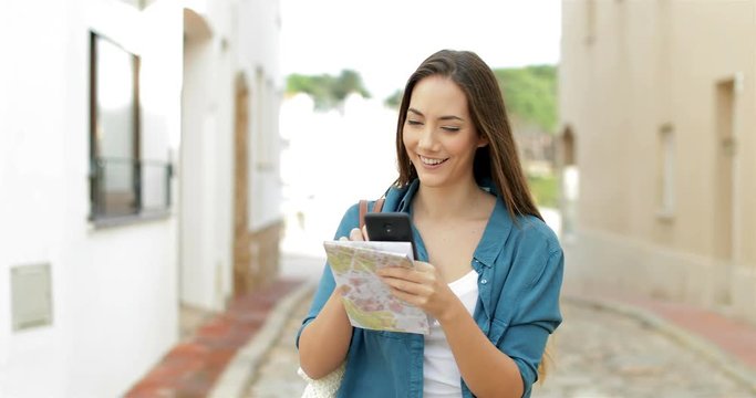 Happy single tourist checking location on smart phone walking in the street on vacation