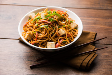 Schezwan hakka noodles with paneer or cottage cheese. Served in a bowl. selective focus