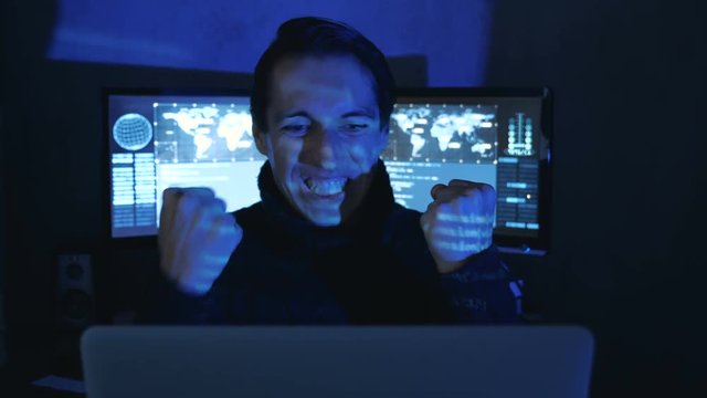 Portrait of Amazed Surprised Professional IT Programmer in a data center filled with monitor screens. Sudden Victory or Success