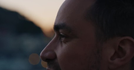 close up portrait attractive young caucasian man on rooftop at sunset chatting enjoying conversation with bokeh city lights in background