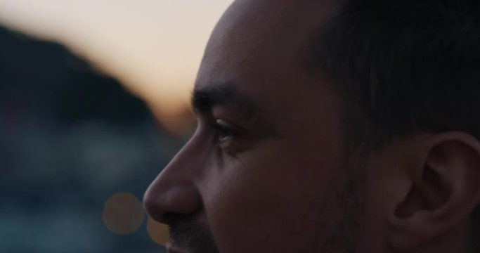 close up portrait attractive young caucasian man on rooftop at sunset chatting enjoying conversation with bokeh city lights in background
