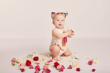 cute baby with flowers on a light background	