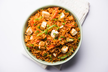 Schezwan paneer fried rice with Szechuan sauce and cottage cheese cubes. served in a bowl or plate or pan. selective focus