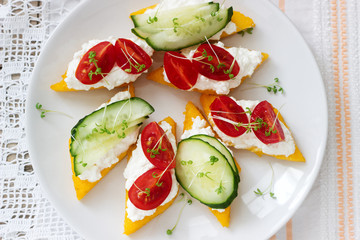 Vegetarian canapes from polenta with cheese, vegetables and cress on a light background. Rustic style.