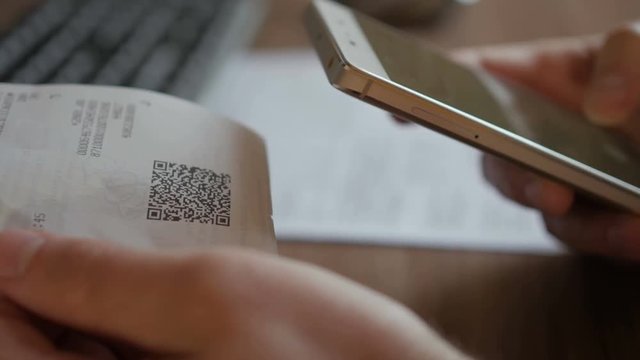 A man scans the QR code on a check from a supermarket.