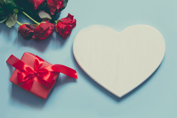 Valentine's card with space for text, giftbox, bouquet red roses on blue. Copy space. View from above.