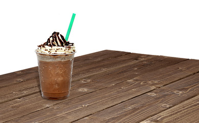 Frappuccino with chocolate sauce, syrup, sherbet in takeaway or to go cup on wooden table at cafe