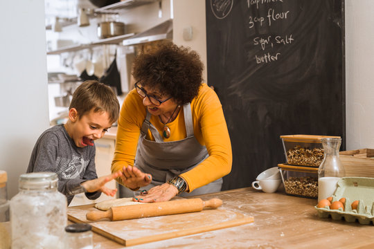 young boy preparing pizza dough with her grandparent