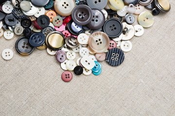 A lot of colorful sewing buttons of different colors of metal and plastic on linen light natural...