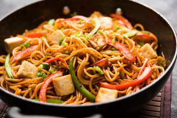Schezwan hakka noodles with paneer or cottage cheese. Served in a bowl. selective focus