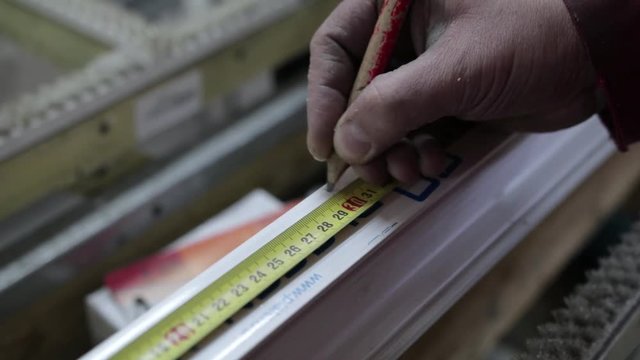 worker notes on a ruler with a pencil how to measure. Close-up, measuring tape measure linear on production