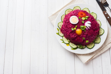 layered salad with herring and beets, carrots and potatoes and eggs close-up on a plate. horizontal copy space