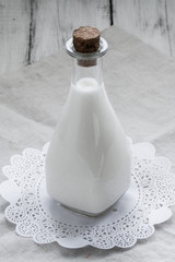 Coconut milk in a vintage bottle on rustic wooden background.