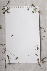 a white sheet of paper on a gray cloth and thyme branches.