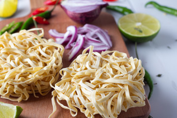 Ingredients for Asian cuisine: noodles, hot peppers, red onions and spices close-up.
