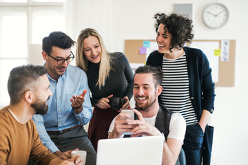 Group of young businesspeople with laptop having meeting in a modern office.
