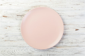 Directy above Empty rose matte plate on white wooden background