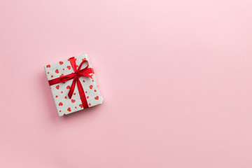 Gift box with red ribbon and heart on pink background, top view with copy space for text