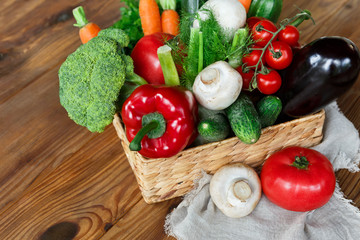 Wicker basket with vegetable assortment on wooden table