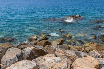 Fototapeta na wymiar Big rocks on the shore of a crystal clear water beach