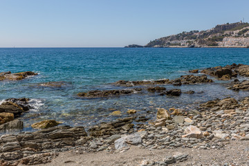 Fototapeta na wymiar Big rocks on the shore of a crystal clear water beach