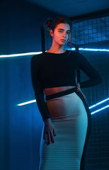 Elegant girl on the background of the cell in the studio with neon lighting