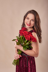 young attractive girl with red roses on a beige background on Valentine's Day February 14