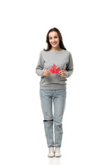 beautiful woman in casual clothes looking at camera and holding maple leaf isolated on white